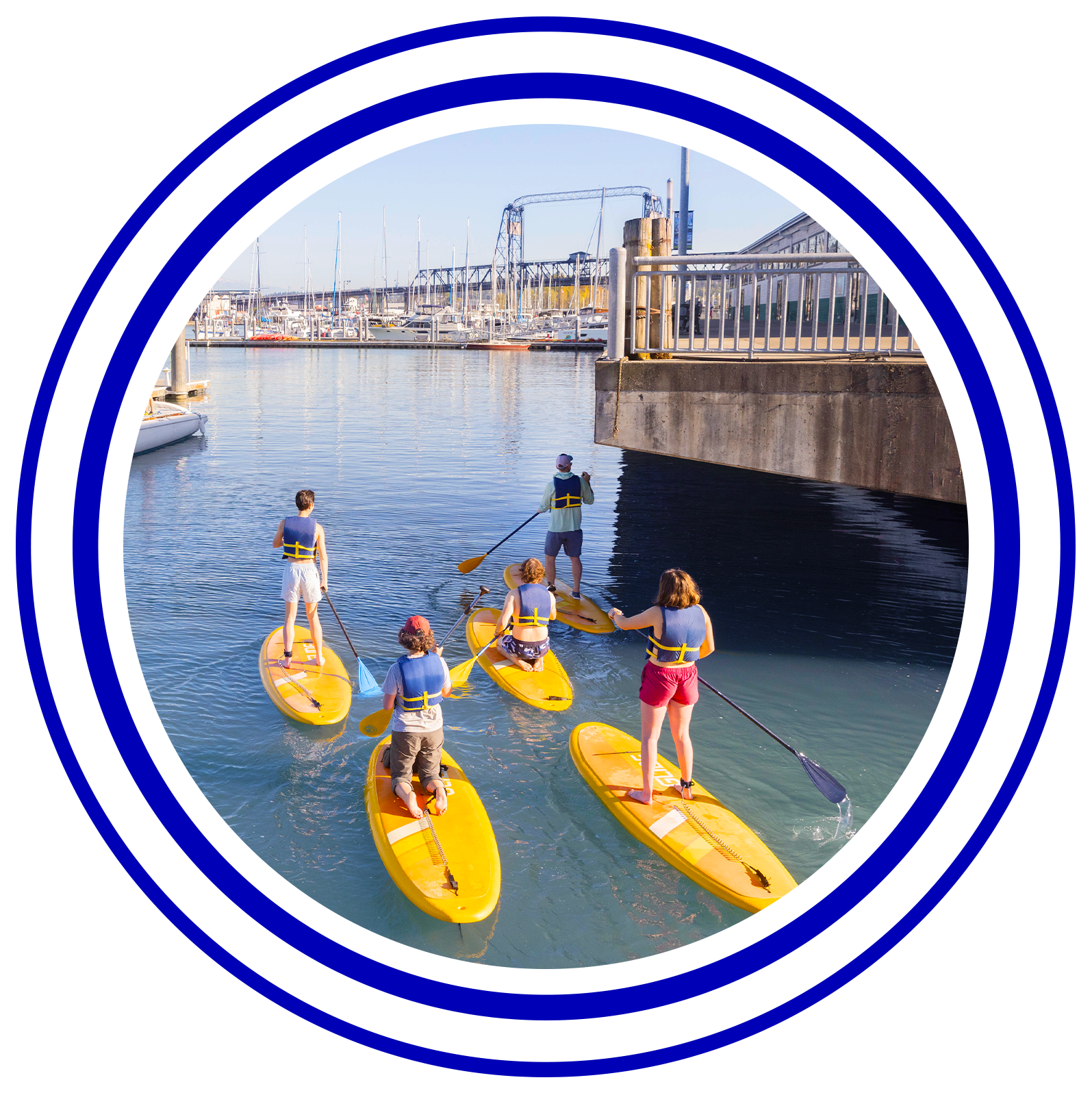 Circular image with colorful rings around it of students paddle boarding.